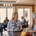 Happy senior women talk while having lunch at nursing home.